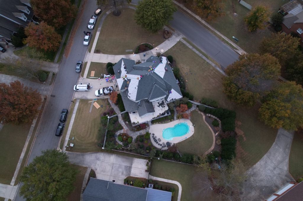 Aerial view of a Cooper roofing jobsite in a North Alabama neighborhood with trucks staged on the drive
