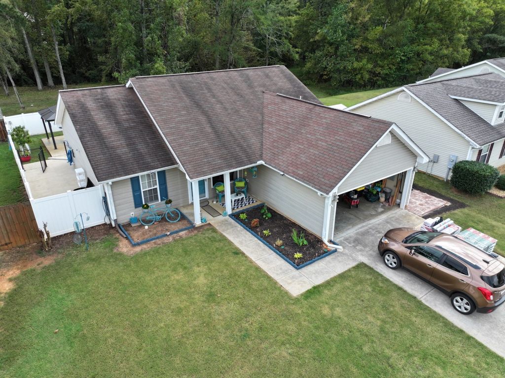 Aerial photograph of a worn, weathered shingle roof before replacement, with new material delivered to the driveway