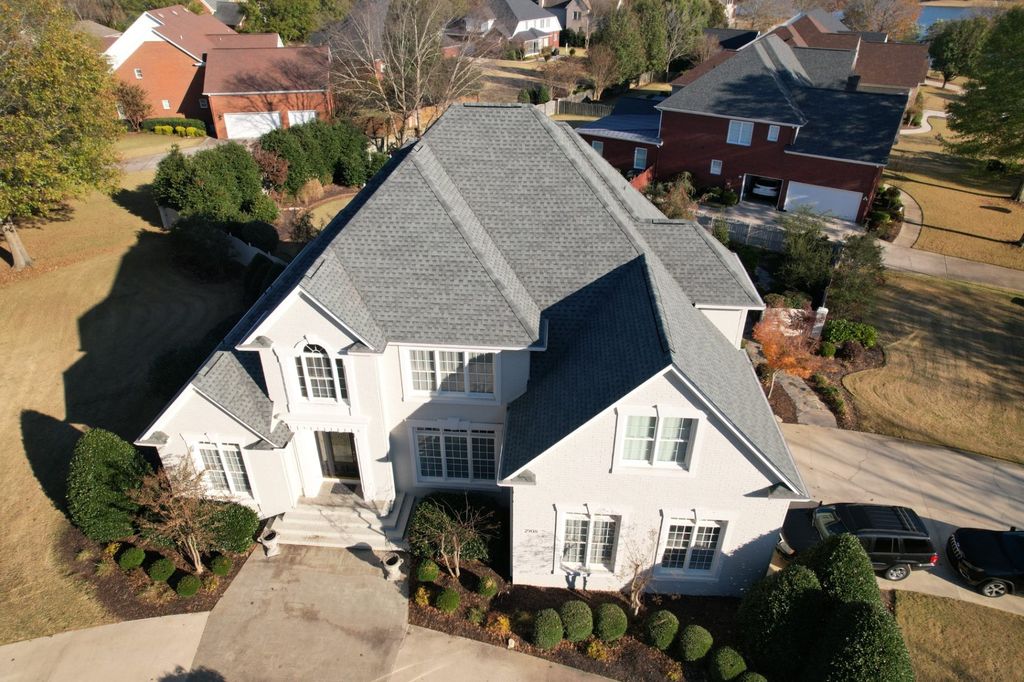 Aerial view of a completed shingle roof on a white brick home