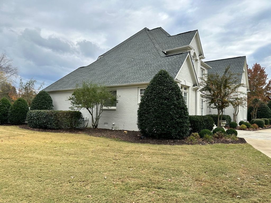 Ground-level view of a completed shingle roof on a white brick home in North Alabama