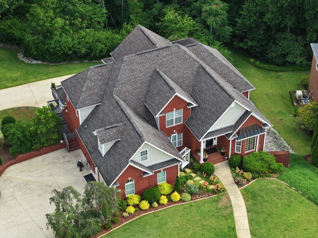 Aerial view of a completed architectural shingle roof on a large multi-gable brick home