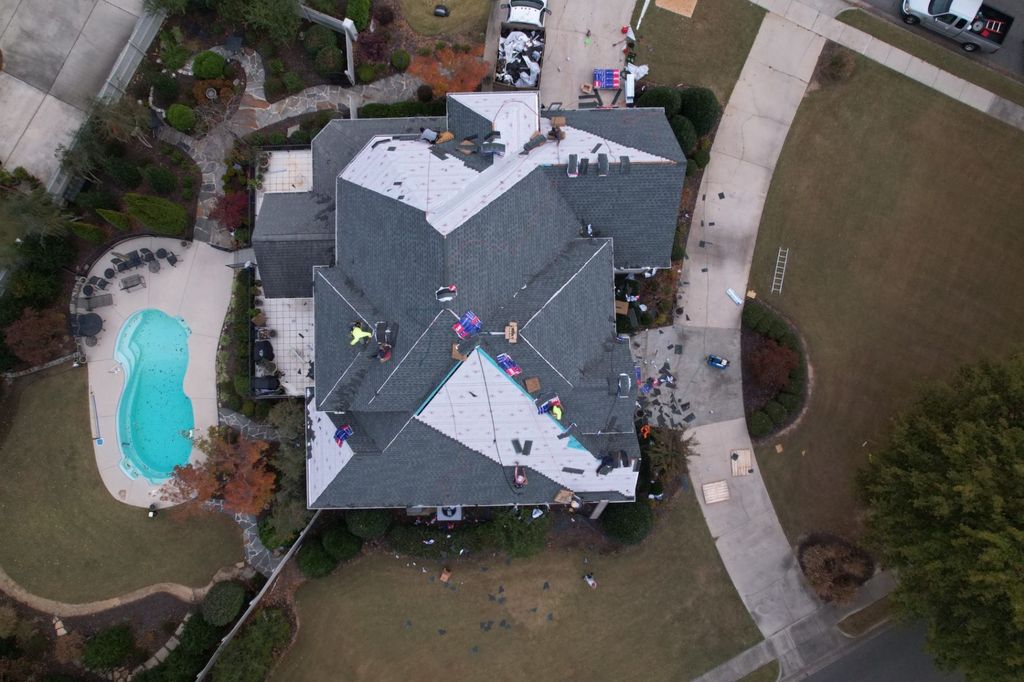 Straight-down drone view of a roof replacement in progress, half underlayment, and half finished shingles