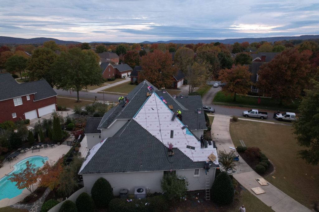 Cooper roofing crew installing GAF architectural shingles on a large home at dusk, photographed by drone