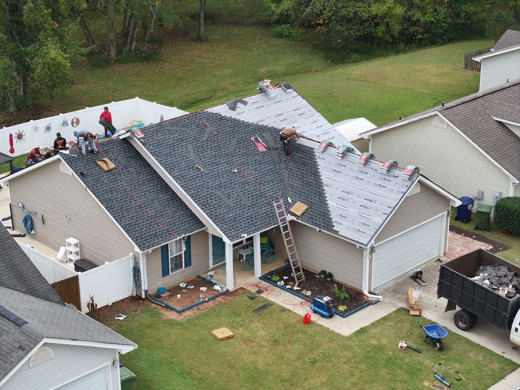 Cooper roofing crew tearing off old shingles and installing synthetic underlayment, photographed by drone