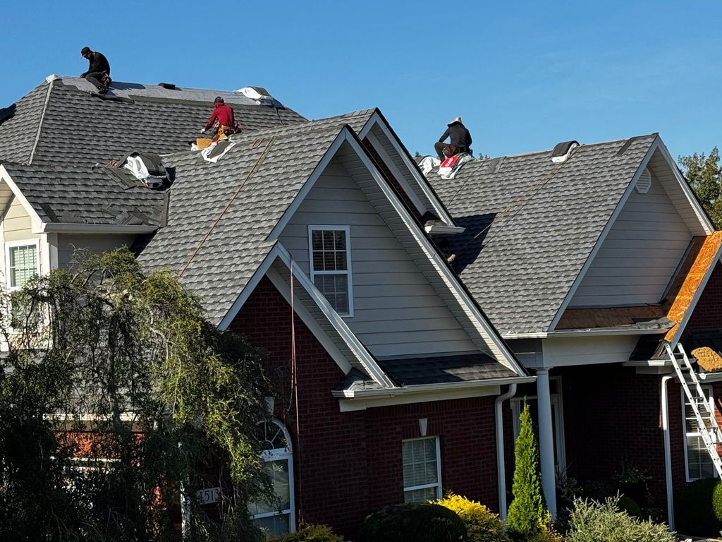 Cooper roofing crew tearing off and replacing shingles on a two-story brick home in Huntsville, Alabama