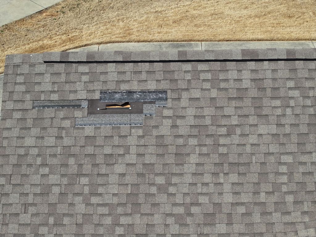 Drone photo of a shingle roof with a section of shingles blown off, exposing the underlayment
